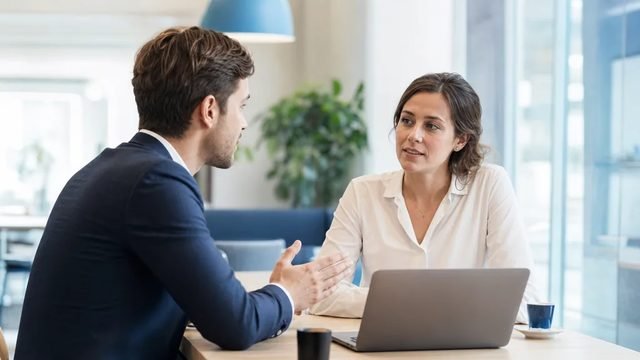 Two professionals in a sales meeting at a wooden table